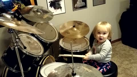 Little girl adorably tries to play the drums