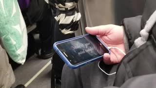 Man watching lyrics on screen on train