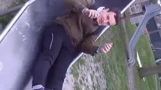 Green jacket slides down tube and falls down in playground