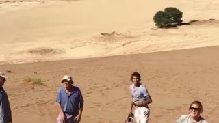 Girls running down sand man falls on face