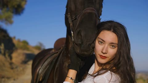 lose-up portrait of confident beautiful horsewoman hugging animal