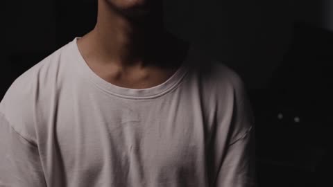 A Man in White Shirt Looking Pensive Against Black Background