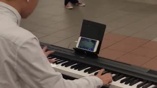 Man playing piano while playing games on phone