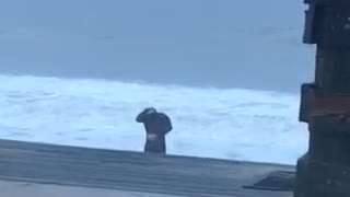 Black wetsuit guy doing stretches on beach