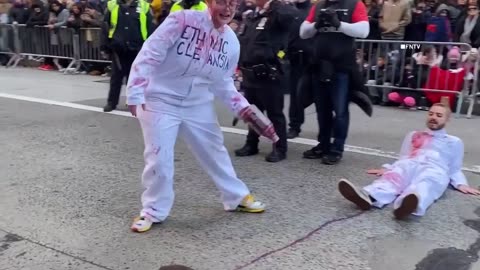 Pro-Palestinian protesters covered in fake blood glue hands to street, disrupting Macy's parade.