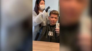 Student gets hair cut by hairdresser in a 'Coronavirus suit'