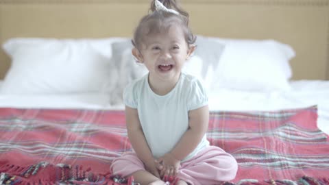 Smiling Baby Girl Sitting on Bed