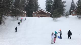Guy sleds down hill, hits bump and tumbles down