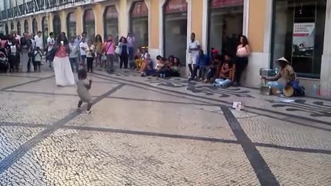 Toddler dances to drumming street performer