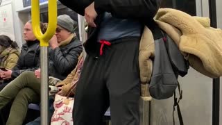 Man in cowboy hat practices his kung fu moves on a handrail on subway train