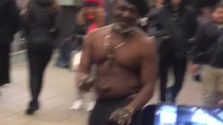 Shirtless man dances to drum beat at subway station