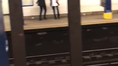 Two guys square dance with each other in subway station