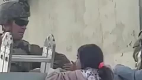 Us soldier lift little girl over the wall in Kabul airport