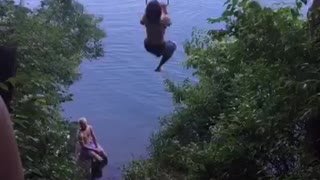 Shirtless guy swinging from tree falls into water
