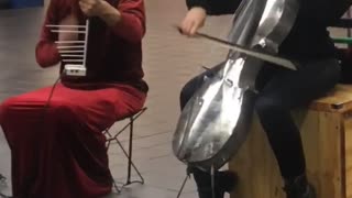 Silver skull and silver bird helmet playing cello violin in subway red dress black suit