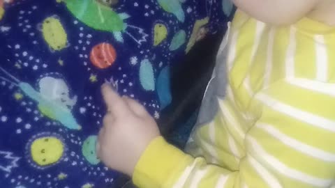 Sweet baby hugs the animals on his blanket