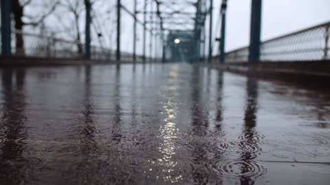 Light Rain Storm Falling with Sound, On a bridge over water with a light at the end.