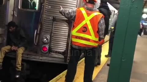 Sad guy sits on the edge of subway train and waits for train to go, attendants tell him to get off