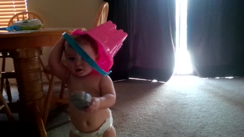 Toddler plays peek-a-boo with bucket on head
