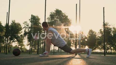 Male Basketball Player Stretching His Legs In An Outdoor Basketball Court