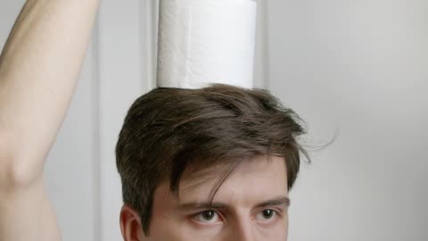 A Man Balancing Toilets Papers On His Head