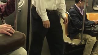 Man in white shirt black pants wiggle dance on subway train