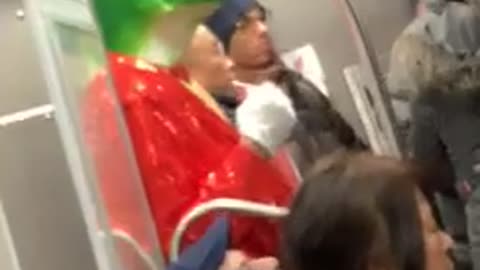 Man on subway train wearing frog mask with red tuxedo