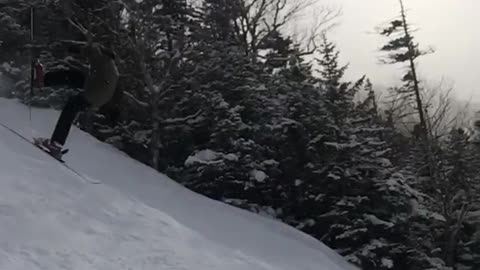 Skier does a jump off cliff and falls on back