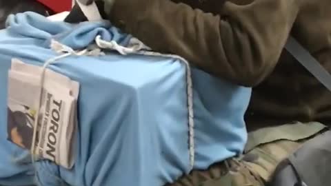 Man cuddles his pet pigeon on top of a blue box, on subway