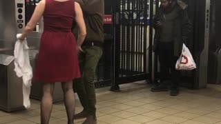 Woman and man dance together next to subway station turnstiles