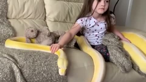 Toddler shows no fear with the pet python while watching cartoons