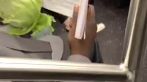 Man eats a whole head of cabbage and reads a book about female body parts on subway train