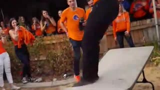 Music orange shirt black hat jumps off roof and breaks folding table