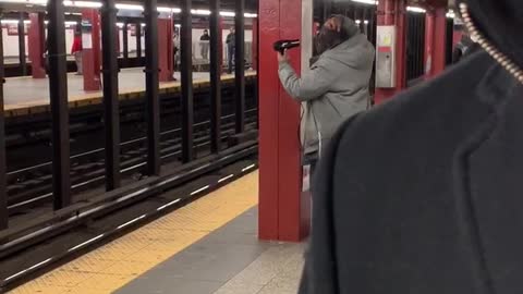 Man uses a blowdryer on his dread inside a subway station