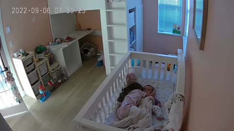 Sweet little girl cuddles baby sister in her crib