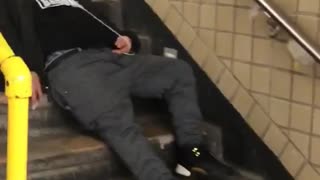 Man black shirt red hat asleep on subway stairs