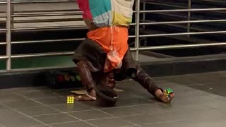 Man orange shirt colorful pants head stand upside down