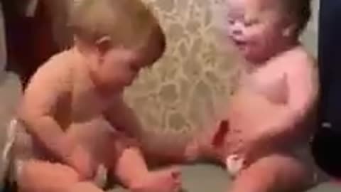 Adorable baby brothers enjoying and laughing in a vibrating chair