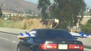 Person driving on freeway with surfboard through back seat windows