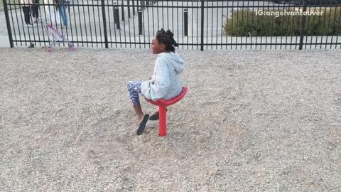 Girl on red spinning chair at park