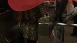 Two people subway turnstile red umbrella hats