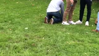 Guy gets pushed over by friend and lands on other friend kneeling on the ground