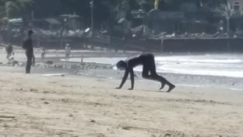 Man in black wetsuit crawling towards beach