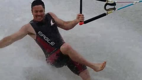 Barefoot waterskiing guy wipe out after tricks