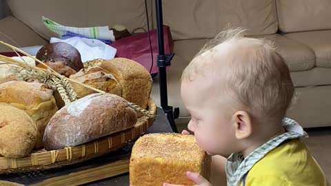 This baby looks very hungry & Cute try to eat whole loaf of bread with his little mouth.