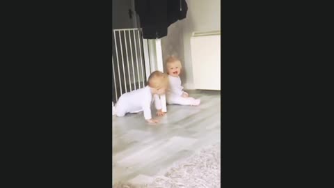 Giggling twins adorably play peek-a-boo with each other