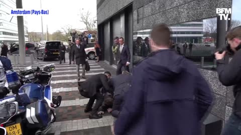 Security guards knock a man to the ground during Macron's visit to the University of Amsterdam