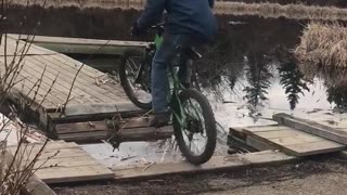 Guy in green bike rides into lake