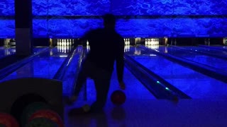 Guy at bowling alley falls when he throws ball