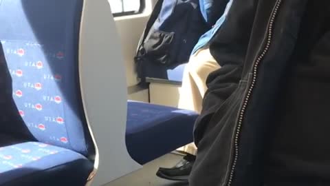 Man clips his fingernails on the back of a bus
